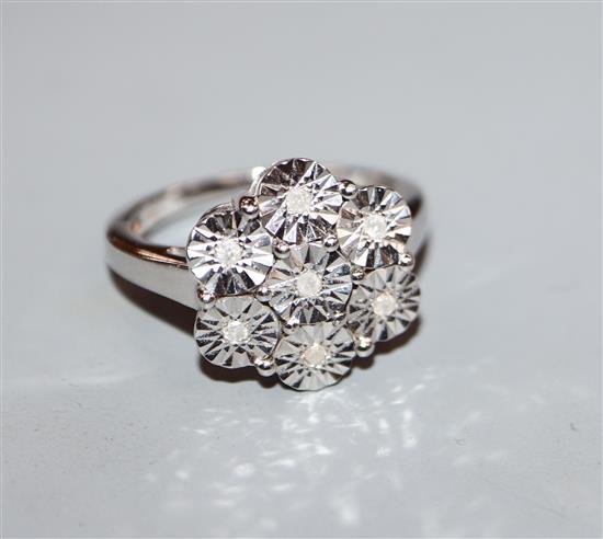 A 9ct white gold and illusion set diamond flower head ring, size N.